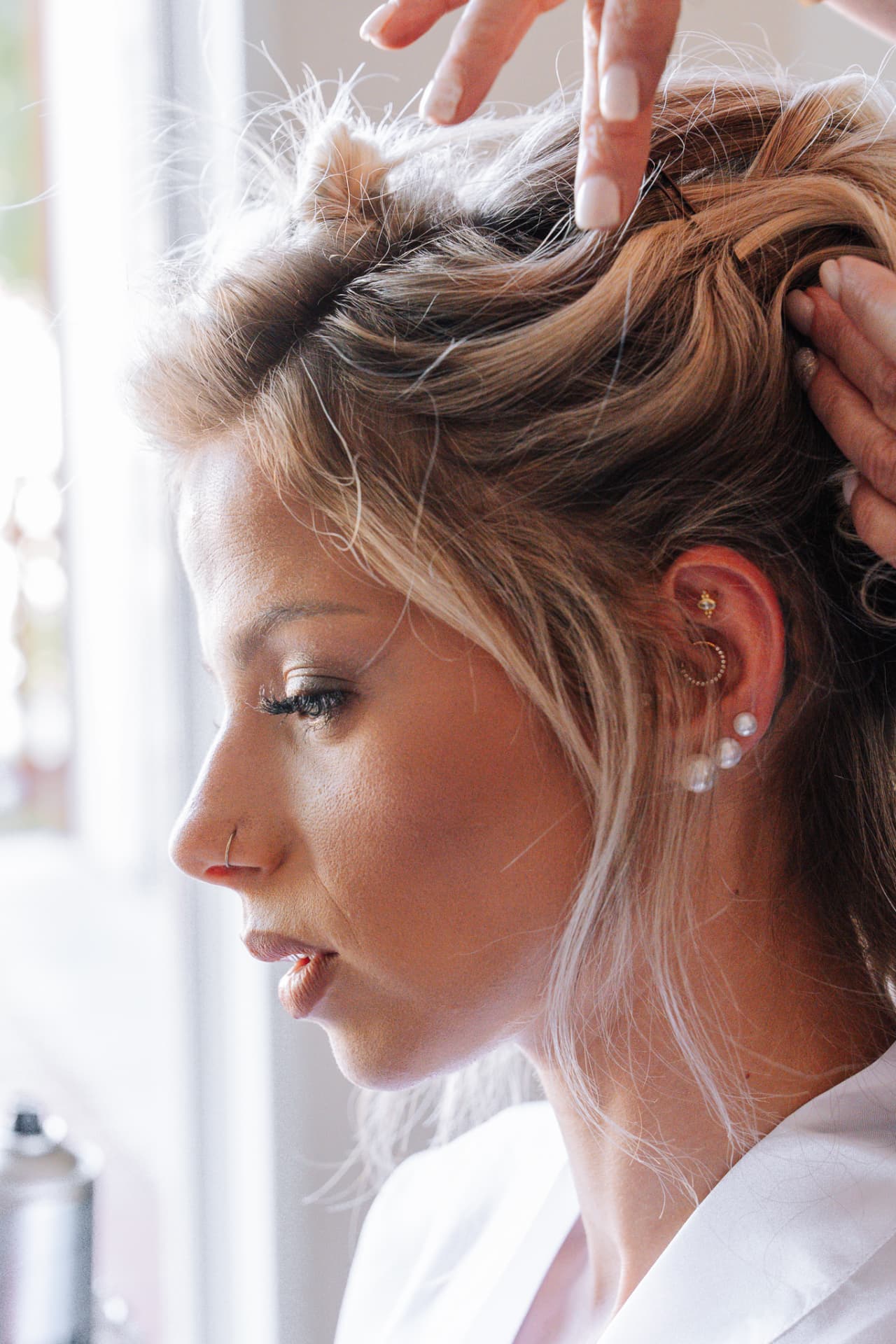 Préparatifs : la coiffure de la mariée près de la fenêtre