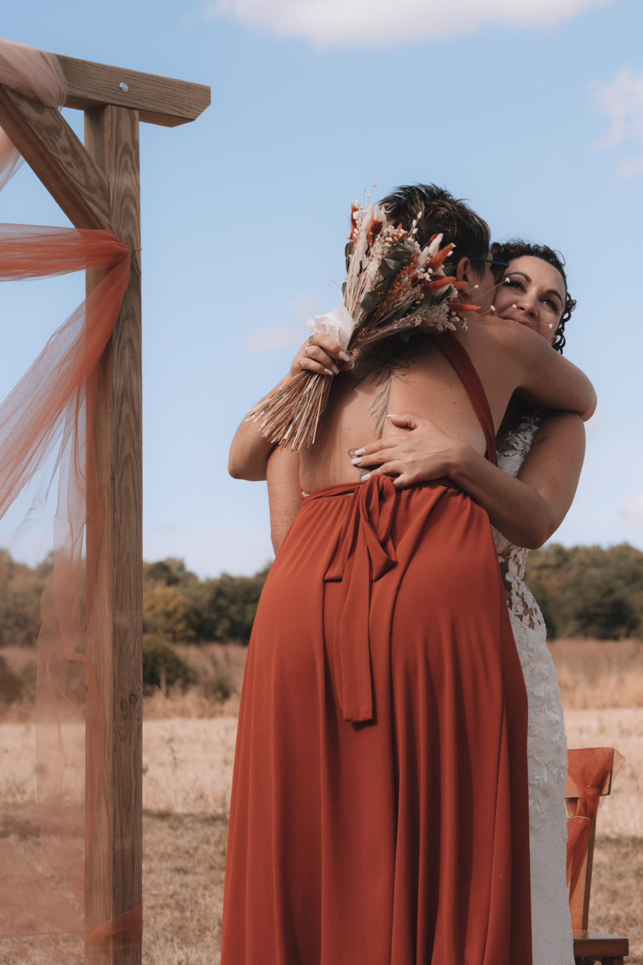 La mariée et une proche s'étreignent près de l'arche