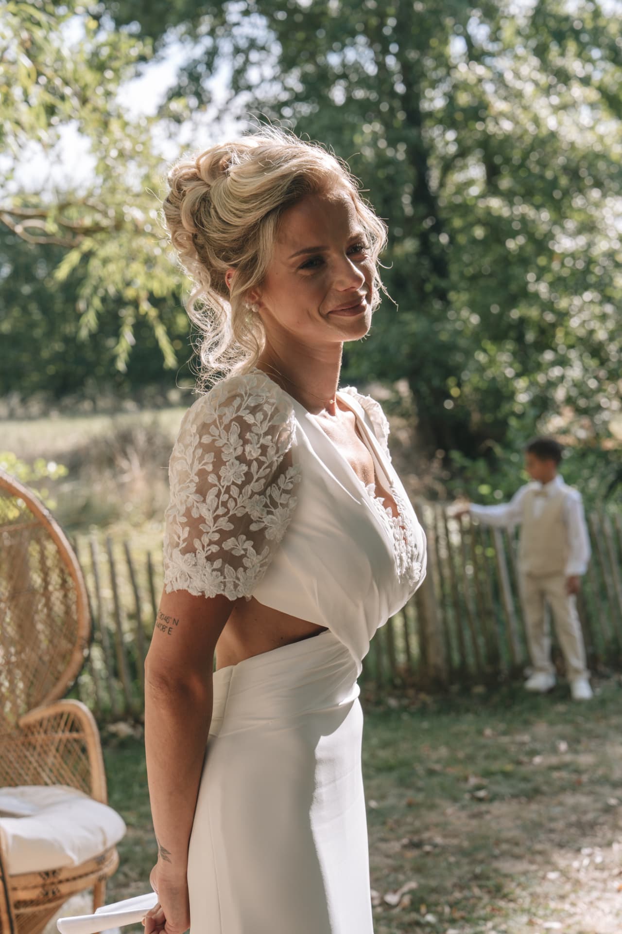 La mariée souriante dans son boléro en dentelle, dans le jardin