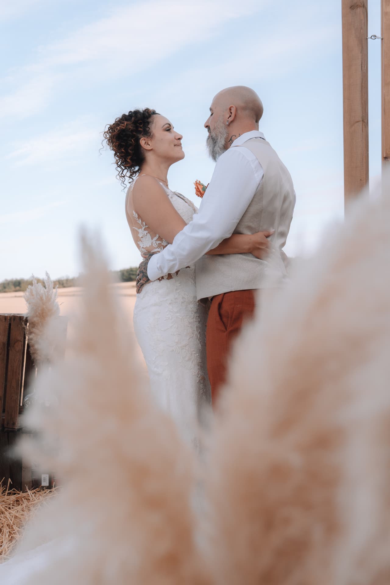 Les mariés face à face derrière des pampas