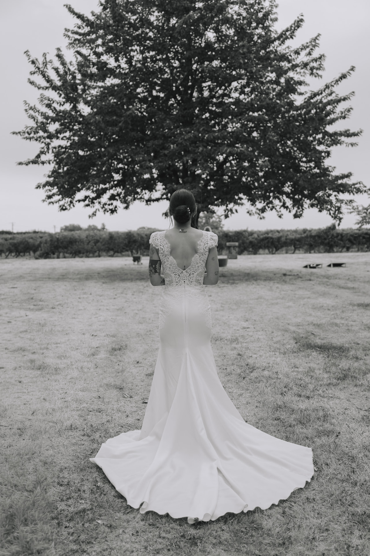 La mariée et sa traîne dans un verger, en noir et blanc
