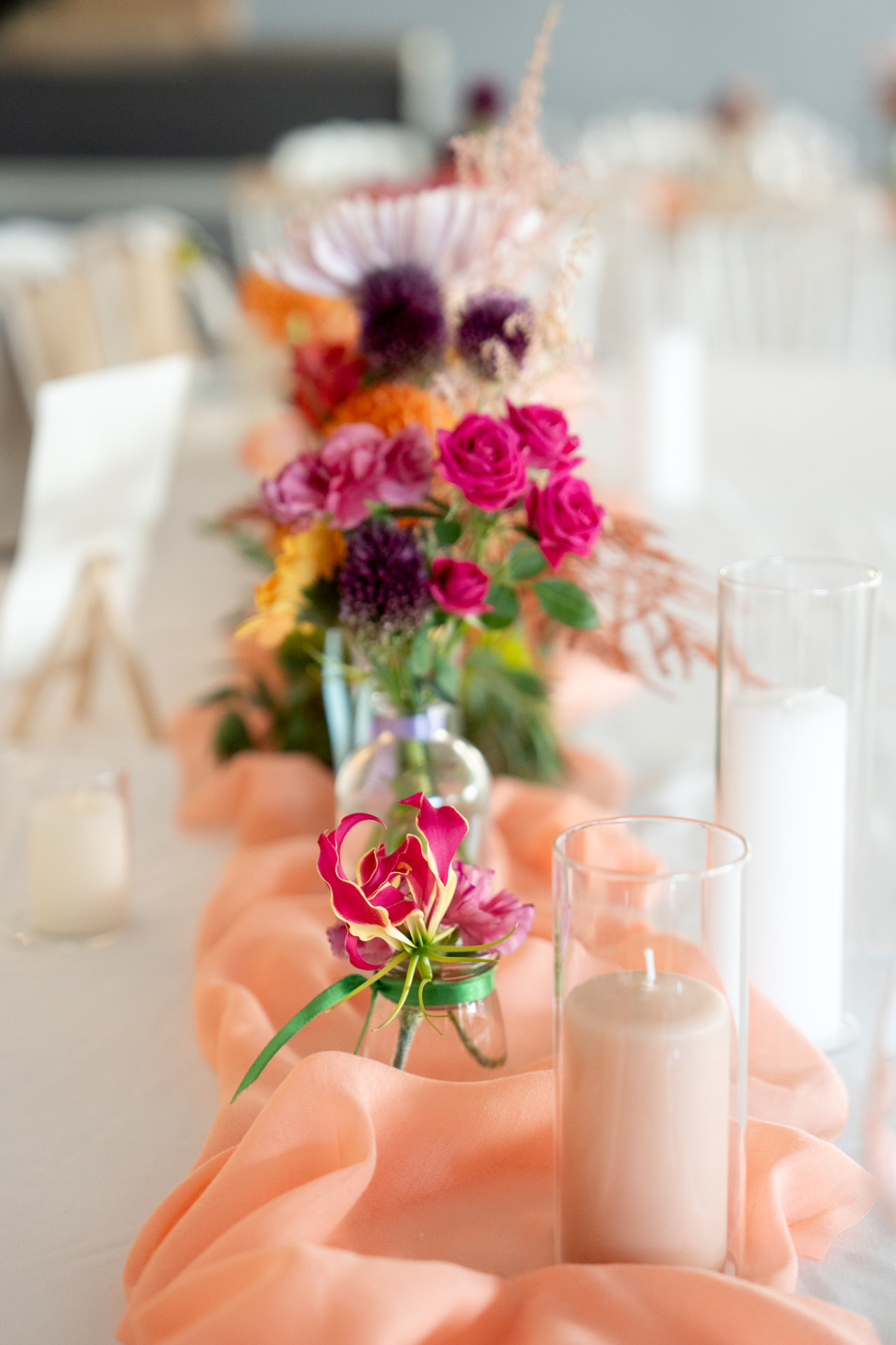 Détail floral coloré et bougies sur une table de réception
